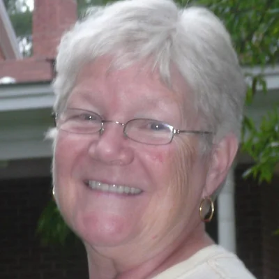 Yvonne smiling in front of the porch at Heartfriends Inn